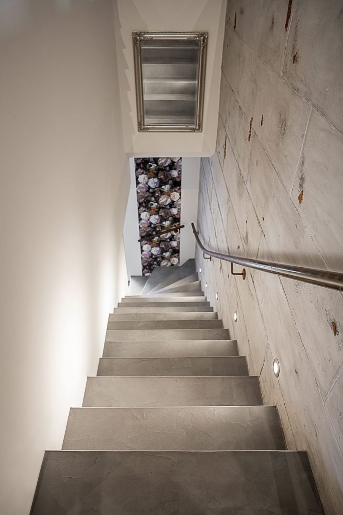 Betontreppenaufgang mit Geländer an der Wand und Beleuchtung
