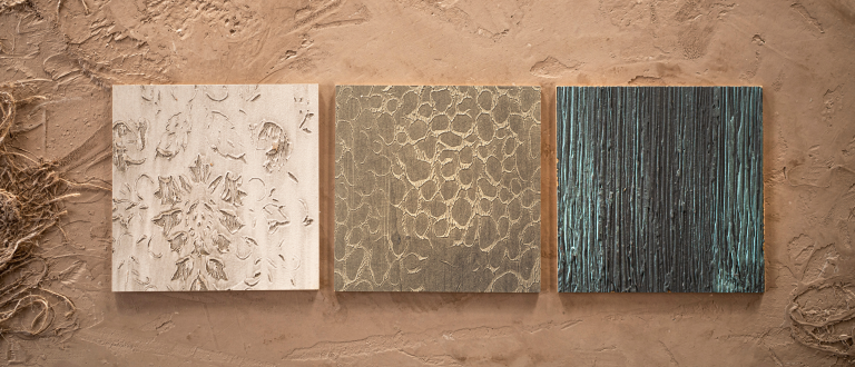 Drei Volimea-Farbmuster auf einem natürlichen, sandigen Boden.