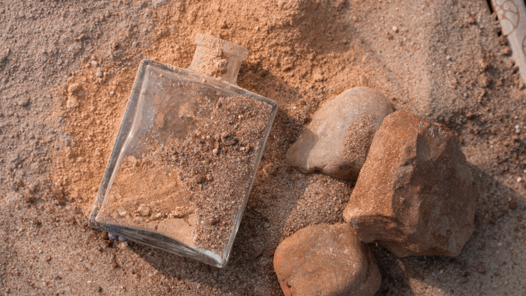 Volimea-Farbpulver in Brauntönen auf Erde, neben Steinen.